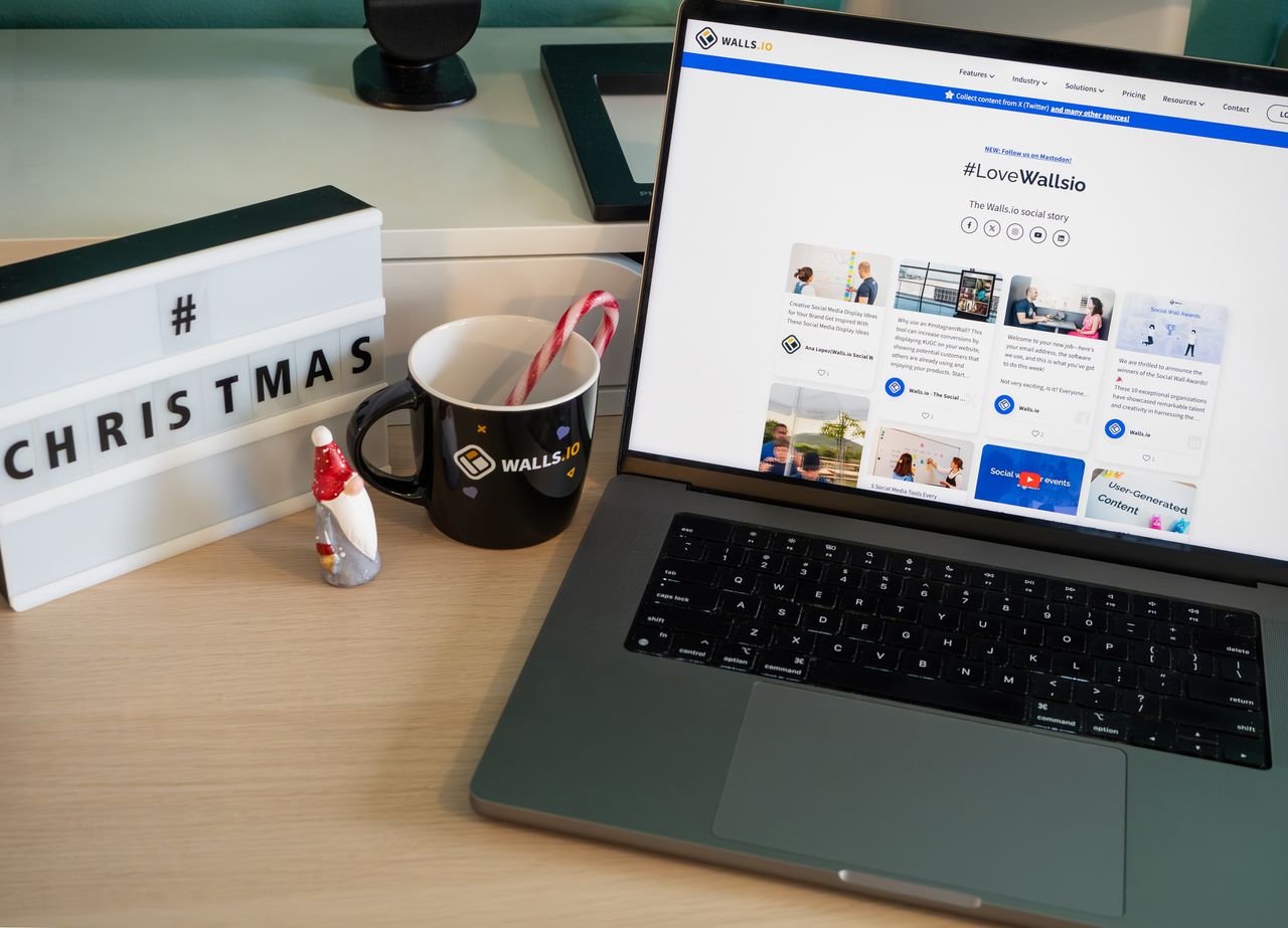 A cozy office setup featuring Christmas decor, a mug, and a laptop screen displaying a website.